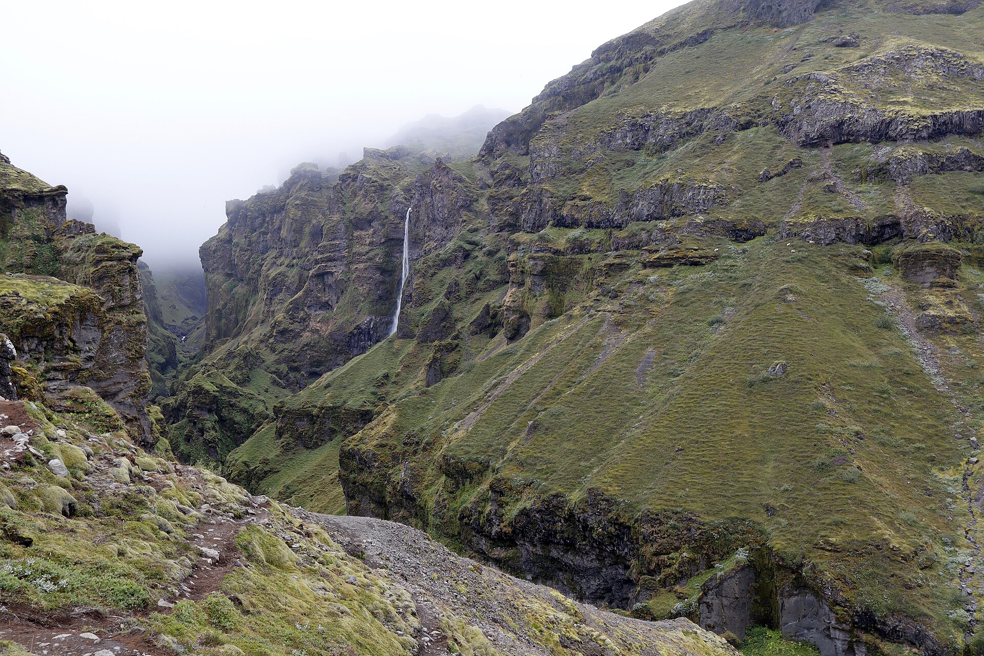 Hangandifoss as a thin ribbon in fog, the trail visible along the near slope