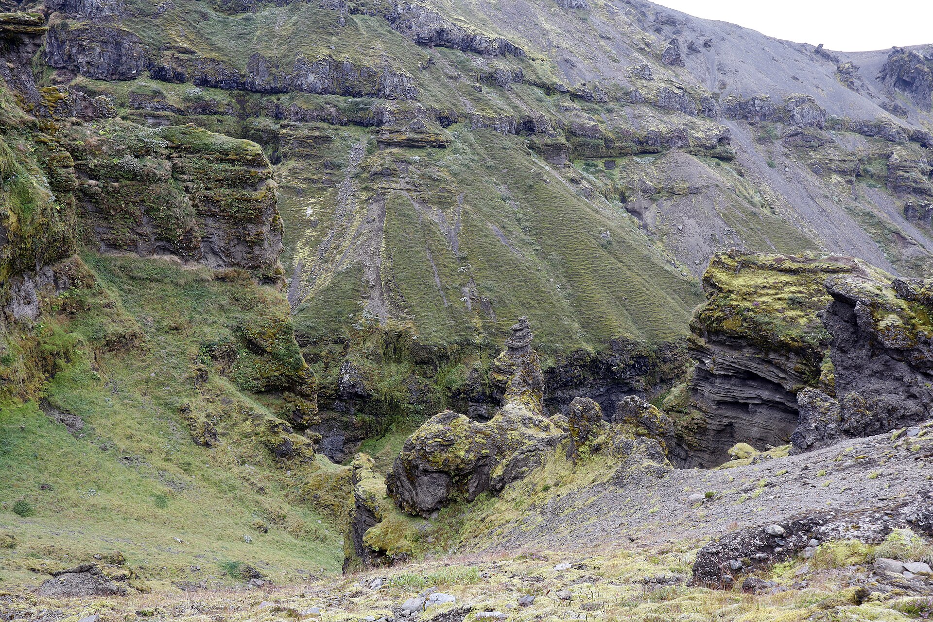 Rock pinnacle rising from the canyon bowl, layered basalt walls behind